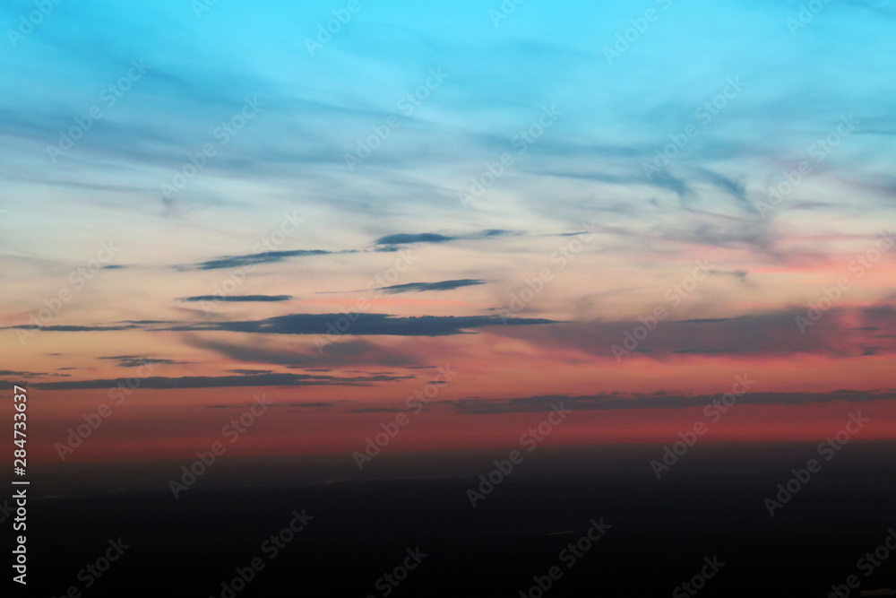Air view of the sky and horizont from above. From Blue, yellow and red to black. The sunset look like a pattern of marble. Nice backdrop / background.