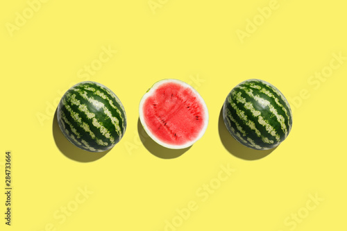 Three halves of watermelon in a row isolated on yellow background photo