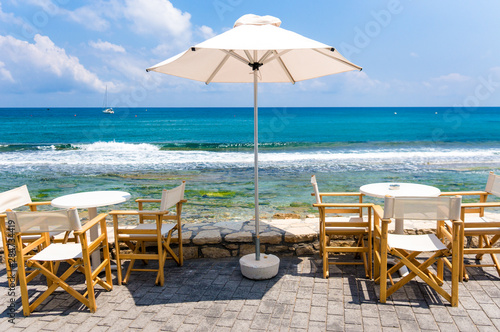 Tables in tavern by the Mediterranean sea coast line. Crete, Greece 