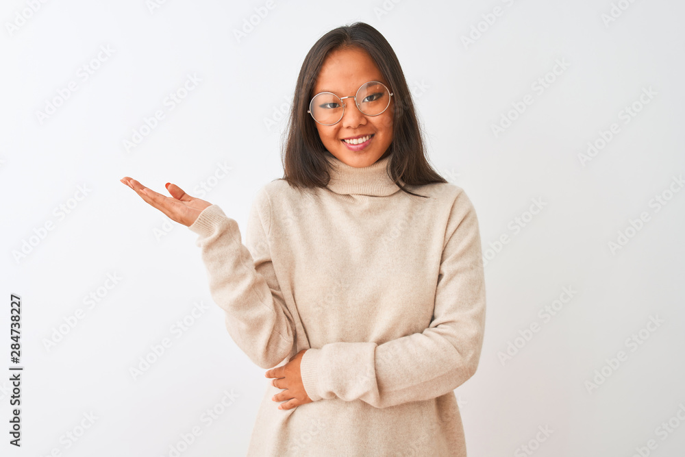 Young chinese woman wearing turtleneck sweater and glasses over isolated white background smiling cheerful presenting and pointing with palm of hand looking at the camera.