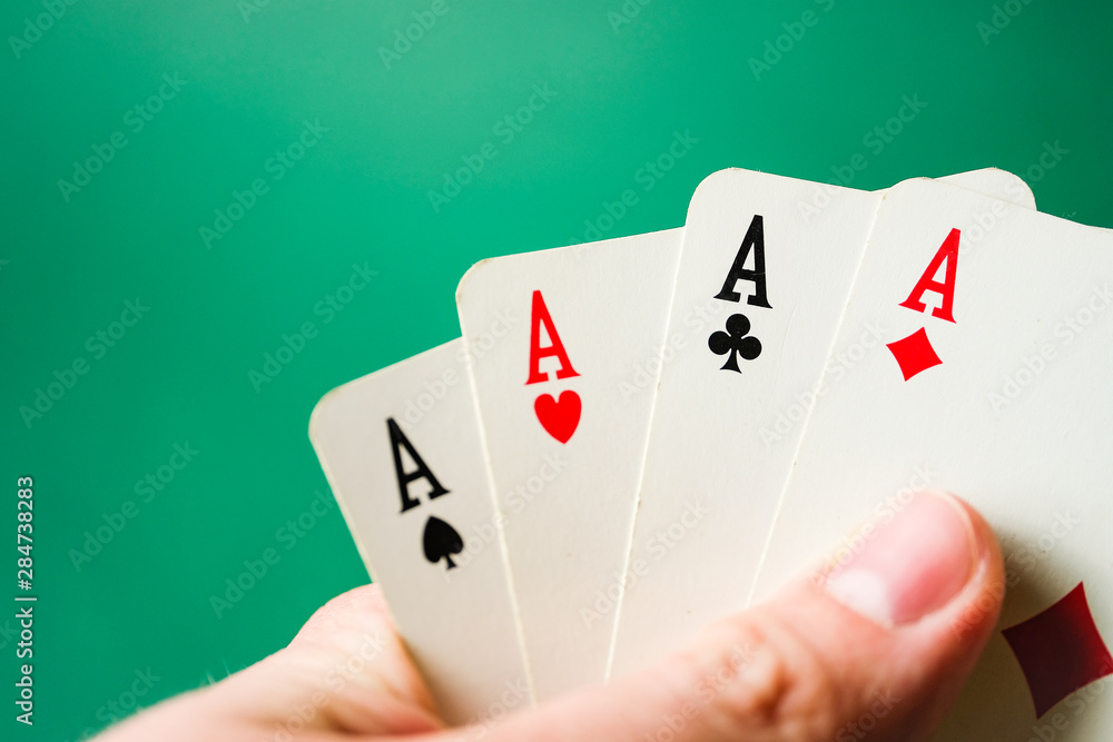 Hand holds four aces on a green background. Hand holds four aces on a green background.