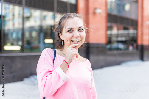 Young Caucasian woman thoughtfully put the finger to her chin on the street.