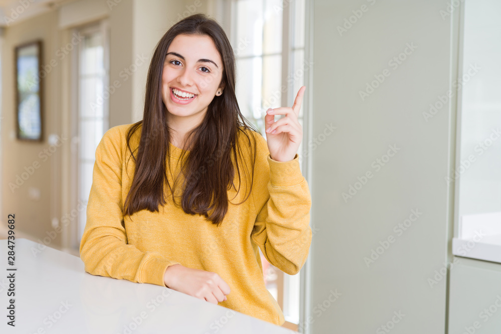 Beautiful young woman wearing yellow sweater with a big smile on face, pointing with hand and finger to the side looking at the camera. Beautiful young woman wearing yellow sweater with a big smile on face, pointing with hand and finger to the side looking at the camera.