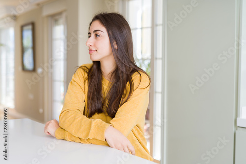 Beautiful young woman wearing yellow sweater looking to side  relax profile pose with natural face with confident smile.