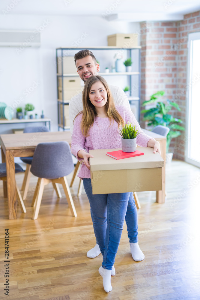 Young beautiful couple in love moving to new home, holding cardboard boxes very happy and cheerful for new apartment Young beautiful couple in love moving to new home, holding cardboard boxes very happy and cheerful for new apartment