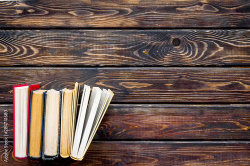 Books on library desk on wooden background top view space for text