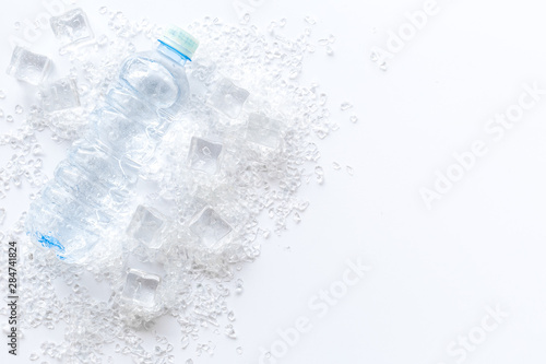 Pile of ice cubes and bottle on white bar desk background top view copyspace