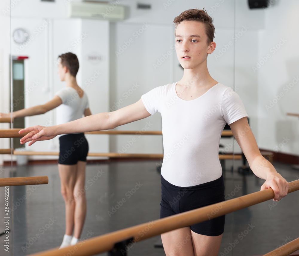 Positive teenager practicing at the ballet barre
