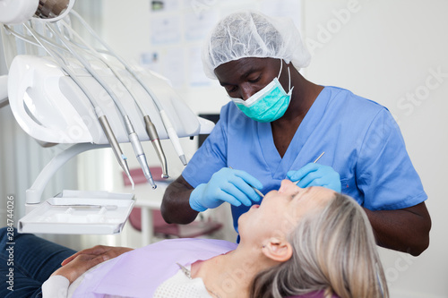 Dentist is treating female patient which is sitting in dental chair in clinic