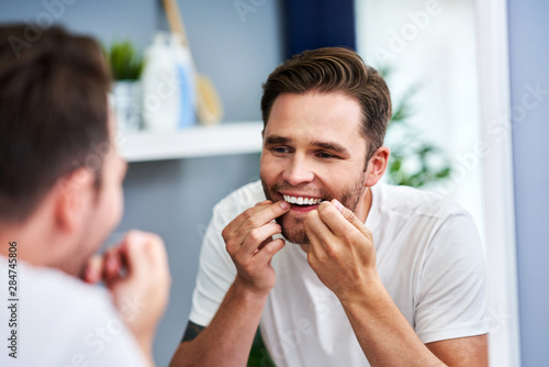 Adult man flossing teeth in the bathroom