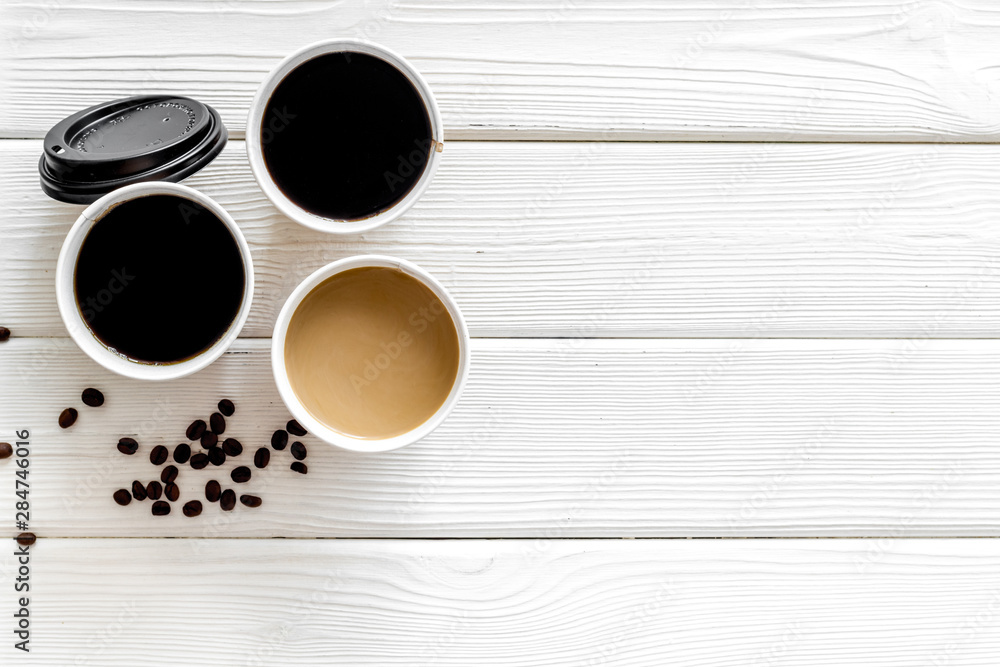 Coffee to take away in paper cups with lids and beans on white wooden table background top view copy space Coffee to take away in paper cups with lids and beans on white wooden table background top view copy space