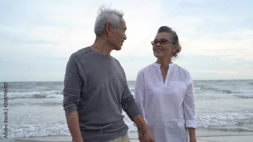 Asian couple senior elder retire resting relax holding hand walking kiss at sunset beach honeymoon family together happiness people lifestyle, Slow motion footage Asian couple senior elder retire resting relax holding hand walking kiss at sunset beach honeymoon family together happiness people lifestyle, Slow motion footage