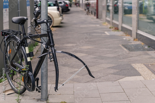 Bike or bicycle lock on steel pole on sidewalk was stolen its front wheel. Stolen wheel bicycle. Abandon vintage bicycle leave on street in Europe.