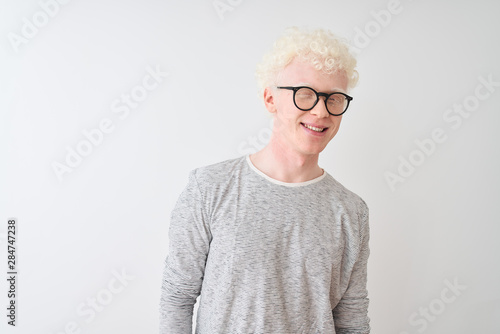 Young albino blond man wearing striped t-shirt and glasses over isolated white background winking looking at the camera with sexy expression, cheerful and happy face.