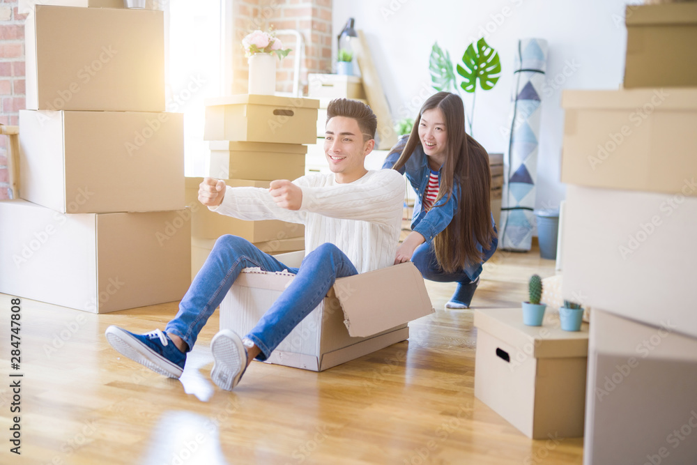 Funny asian couple having fun, riding inside cardboard box smiling happy, very excited moving to a new house Funny asian couple having fun, riding inside cardboard box smiling happy, very excited moving to a new house