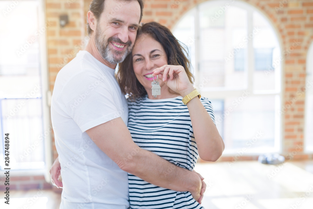 Fototapeta premium Middle age senior romantic couple holding and showing house keys smiling happy for moving to a new home
