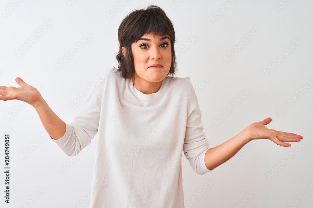 Young beautiful woman wearing casual t-shirt standing over isolated white background clueless and confused expression with arms and hands raised. Doubt concept. Young beautiful woman wearing casual t-shirt standing over isolated white background clueless and confused expression with arms and hands raised. Doubt concept.