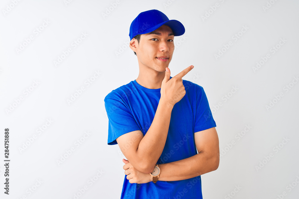Chinese deliveryman wearing blue t-shirt and cap standing over isolated white background cheerful with a smile of face pointing with hand and finger up to the side with happy and natural Chinese deliveryman wearing blue t-shirt and cap standing over isolated white background cheerful with a smile of face pointing with hand and finger up to the side with happy and natural