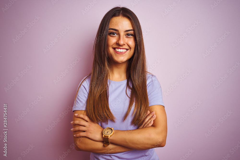 Obraz premium Young beautiful woman wearing casual t-shirt standing over isolated pink background happy face smiling with crossed arms looking at the camera. Positive person.