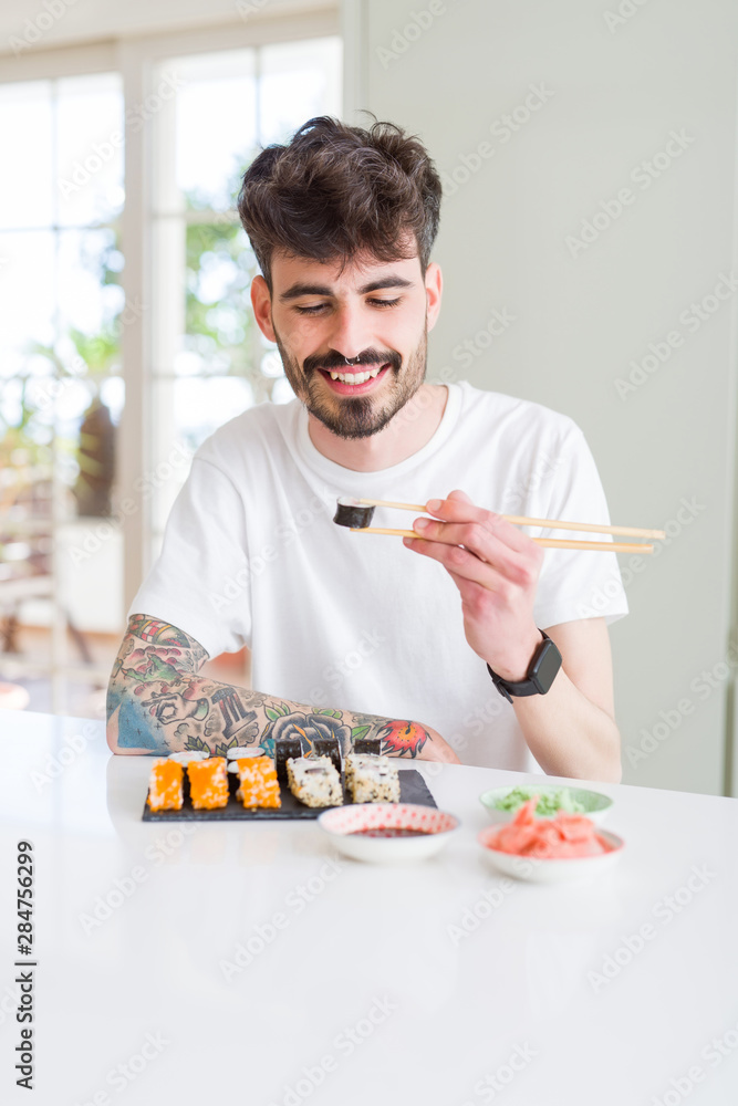 Young man eating sushi asian food using choopsticks Young man eating sushi asian food using choopsticks
