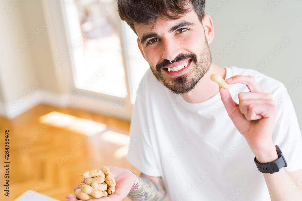 Young man eating peanuts, close up of hand with a bunch of healthy nuts Young man eating peanuts, close up of hand with a bunch of healthy nuts