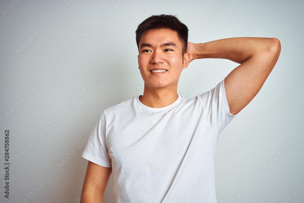 Young asian chinese man wearing t-shirt standing over isolated white background smiling confident touching hair with hand up gesture, posing attractive and fashionable Young asian chinese man wearing t-shirt standing over isolated white background smiling confident touching hair with hand up gesture, posing attractive and fashionable