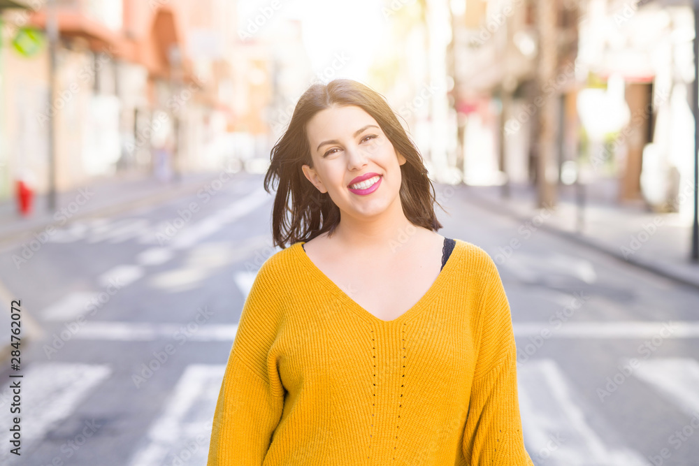 Fototapeta premium Beautiful young woman smiling cheerful walking on the street on a sunny day, casual pretty girl at the town