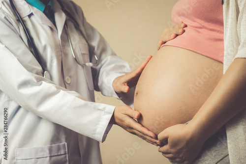 Happy pregnant woman visit gynecologist doctor at hospital or medical clinic for pregnancy consultant. Doctor examine pregnant belly for baby and mother healthcare check up. Gynecology concept. photo