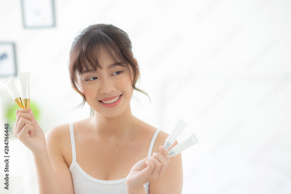 Beautiful portrait young asian woman holding and presenting cream or lotion product, beauty asia girl show cosmetic makeup and moisturizing for skin care, healthy care and wellness concept. Beautiful portrait young asian woman holding and presenting cream or lotion product, beauty asia girl show cosmetic makeup and moisturizing for skin care, healthy care and wellness concept.