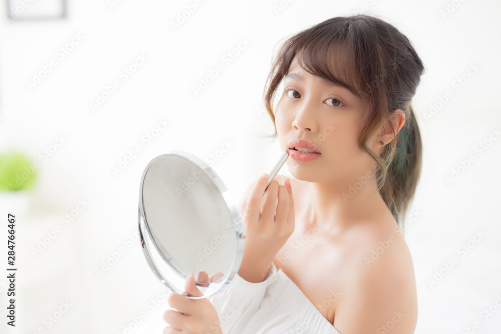 Beautiful portrait young asian woman looking mirror applying makeup lipstick at room, beauty lips asia girl makeup and cosmetic fashion on mouth at home, lifestyle and health care concept. Beautiful portrait young asian woman looking mirror applying makeup lipstick at room, beauty lips asia girl makeup and cosmetic fashion on mouth at home, lifestyle and health care concept.