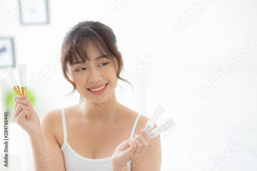 Beautiful portrait young asian woman holding and presenting cream or lotion product, beauty asia girl show cosmetic makeup and moisturizing for skin care, healthy care and wellness concept.