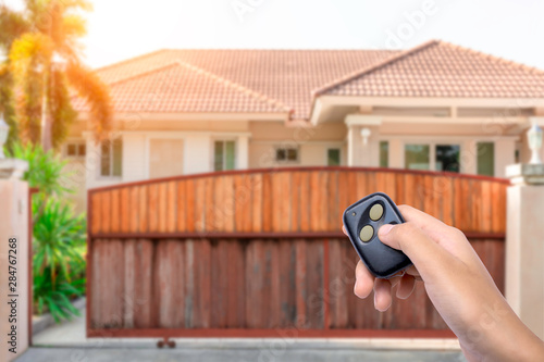 Woman hand holding and using remote control to open the auto gate. Wireless technology concept. 