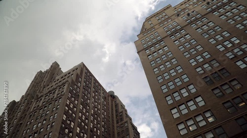Generic day time establishing shot vertical look straight up view of New York City style apartment or office buildings with clouds passing overhead. Typical scene setting in urban real estate