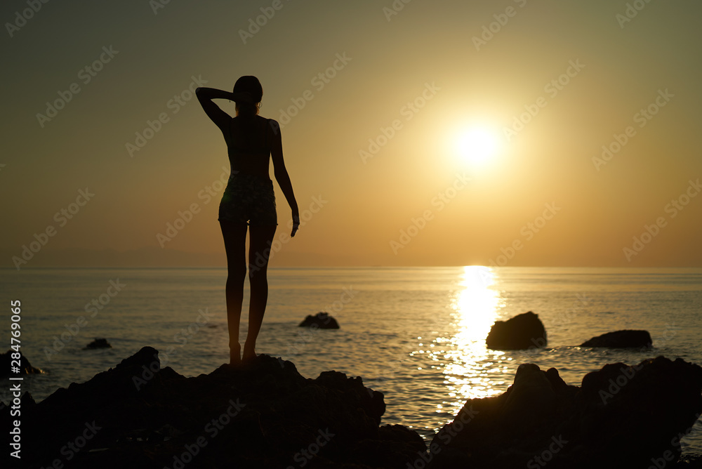 silhouette of a girl against the setting sun in the sea