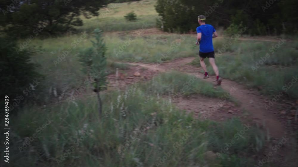 Man trail running on a rocky path in the park. Close to medium shot. Twilight. Low key Man trail running on a rocky path in the park. Close to medium shot. Twilight. Low key