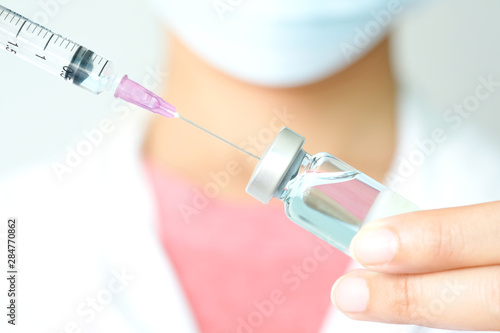 doctor's hand holds a syringe and a blue vaccine bottle at the hospital. Health and medical concepts