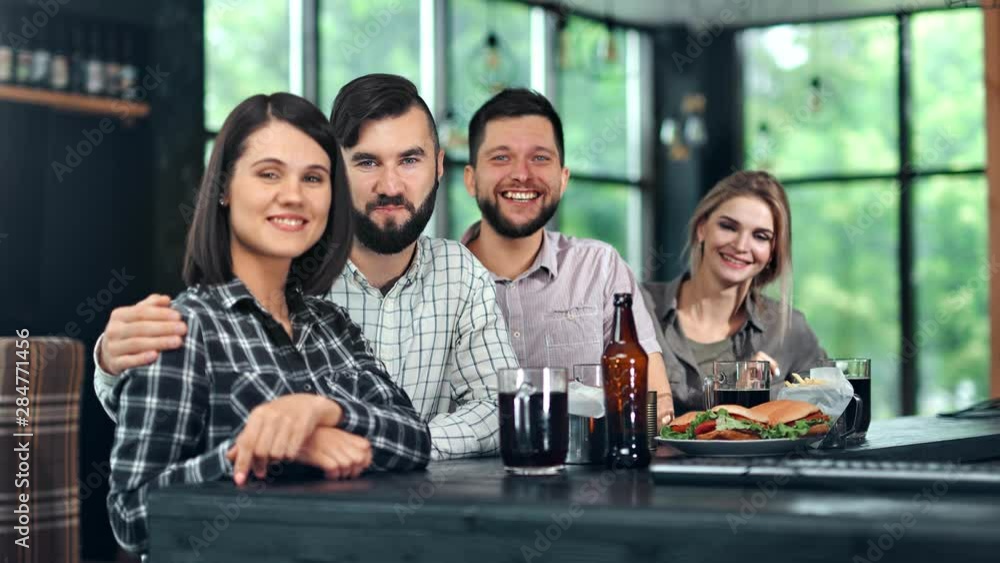 Adorable young people smiling posing looking at camera during informal meeting at pub Adorable young people smiling posing looking at camera during informal meeting at pub