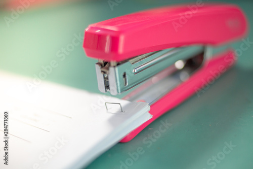 The pink stapler does not pierce through many sheets of paper.shallow focus effect. photo