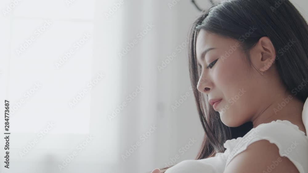 Asian pregnant mother is sitting looking at her belly and smiling while sitting on the bed at her house. Asian pregnant mother is sitting looking at her belly and smiling while sitting on the bed at her house.