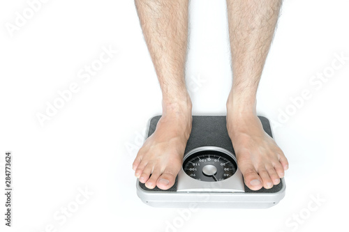 Legs of men standing on scales weight on white background Concept of healthy lifestyle and sport