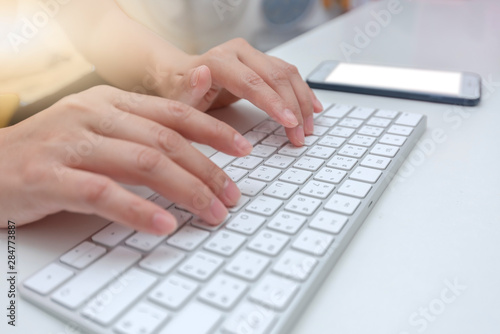 Female office worker typing on the keyboard,working at home office hand on keyboard close up