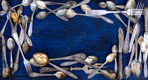 Vintage cutlery - spoons, forks and knives on an old wooden background.