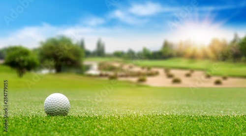 White Golf ball on green course to be shot on blurred beautiful landscape of golf course in bright day time with copy space. Sport, Recreation, Relax in holiday concept	 photo