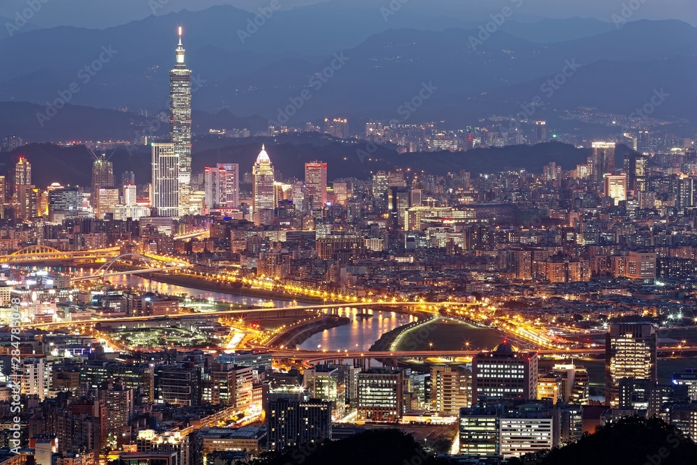 Aerial panorama of Downtown Taipei at night with view of bridges over Keelung River & landmark Tower amid skyscrapers in Xinyi Financial District~ Romantic nightscape of a busy city in a gloomy mood