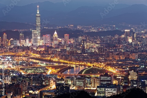 Aerial panorama of Downtown Taipei at night with view of bridges over Keelung River   landmark Tower amid skyscrapers in Xinyi Financial District  Romantic nightscape of a busy city in a gloomy mood