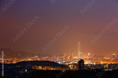 Night scenery of Taipei  the vibrant capital city of Taiwan  with view of landmark Tower among high-rise buildings in Xinyi district   dazzling city lights in downtown glistening in misty twilight