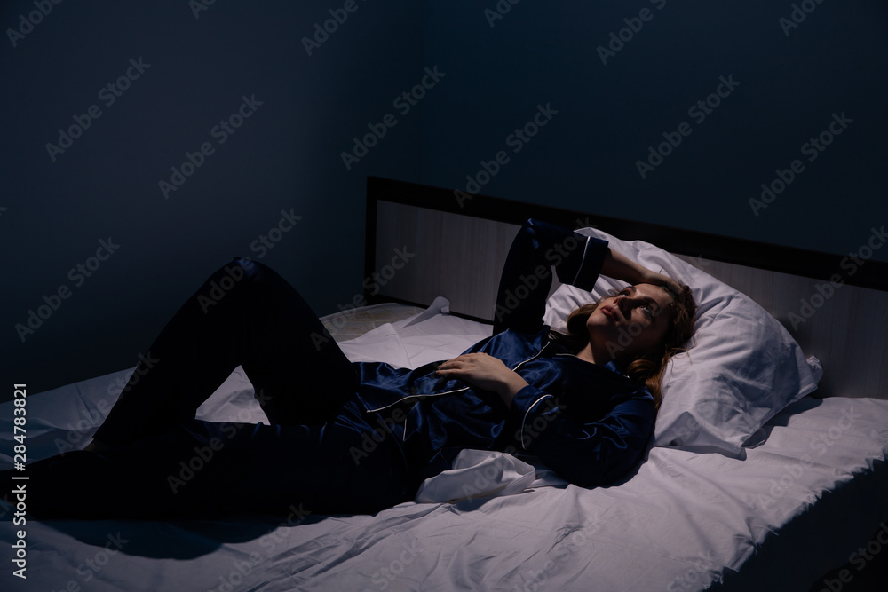 Fototapeta premium Sleepless handsome lady lying in the bed at night.
