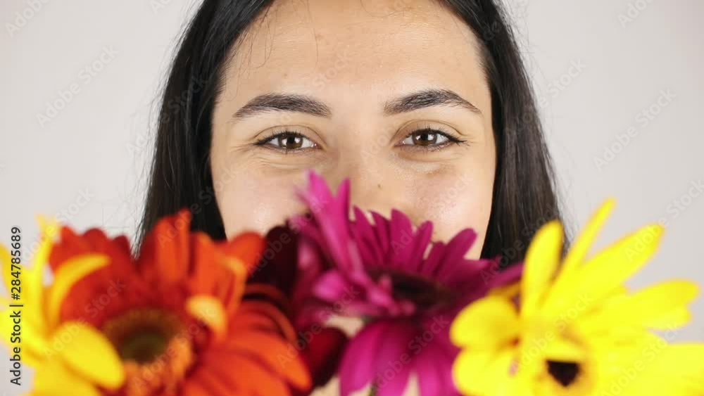 The girl face close up with a bouquet flowers. Portrait of a pretty young woman sniffing a bouquet flowers on grey background The girl face close up with a bouquet flowers. Portrait of a pretty young woman sniffing a bouquet flowers on grey background
