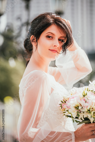 Wedding. Young beautiful bride posing in white dress and veil. Ease, real emotions. Soft light summer portrait. Girl looking at camera