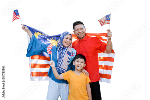 proud malaysian family holding malaysia flag in front of their house on independence day photo